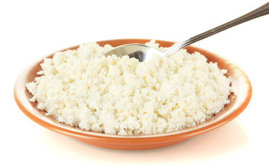 Spoon scoops of cottage cheese in a plate on white background
