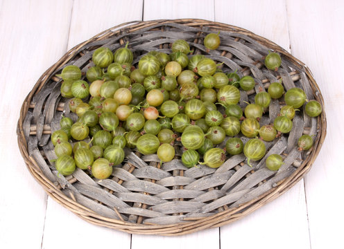 Green gooseberry on wicker mat on wooden background