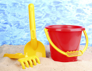 Children's beach toys on sand on water background