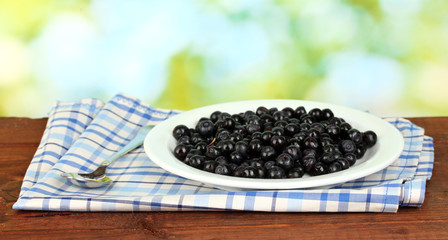 Fresh blueberries in plate on green background