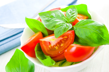 Fresh tomatoes with basil leaves in a bowl
