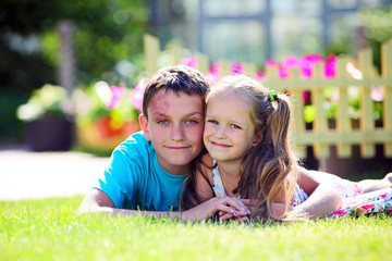 Cute brother and sister lying on the grass outdoors