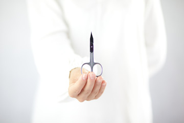Kobieta trzymająca w ręku nożyczki do manicure - obrazy, fototapety, plakaty