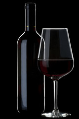 Glass of red wine and a bottle isolated over black background