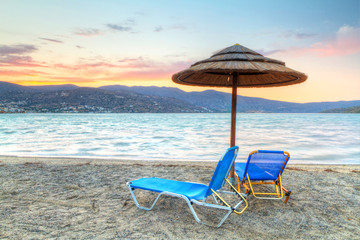 Deckchairs with parasol at Mirabello Bay at sunset, Greece
