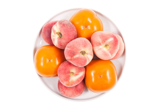 Fresh persimmon and peach isolated on plate