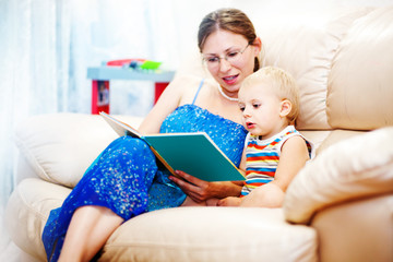 Young mother with her baby holding book at home