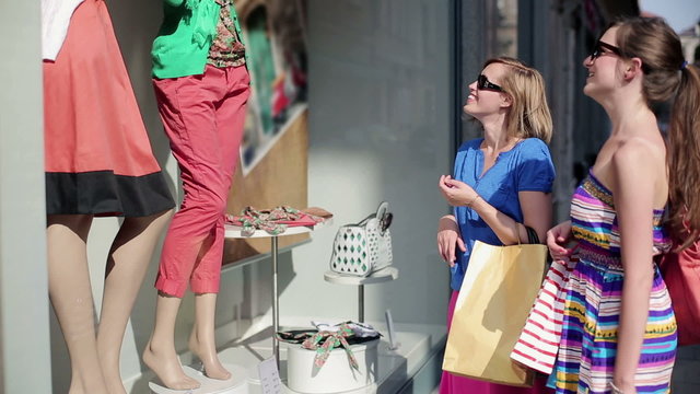 Female friends with shopping bags by the shop window