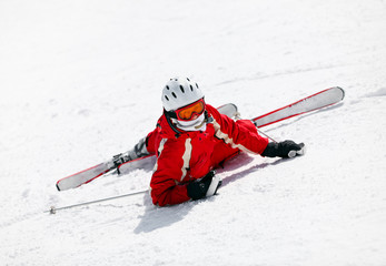 Female skier looking at camera after falling down on slope