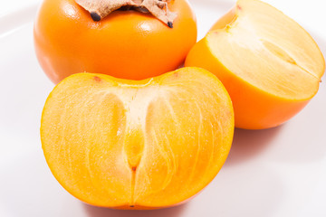 Fresh persimmons on plate isolated on white