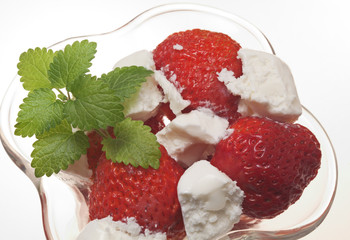 Strawberry with ice-cream and mint in a glass vase on a white ba