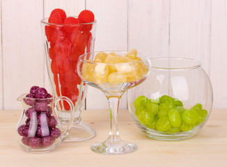 Color candies in glasses on wooden background
