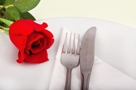 Closeup of rose, plate and silver cutlery