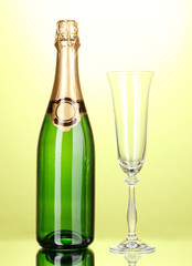 Bottle of champagne and goblet on green background