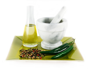 Mortar and pestle with bottle of oil, chillies, spices isolated