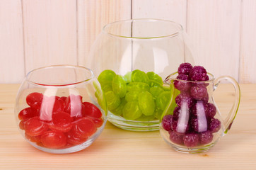 Color candies in glasses on wooden background