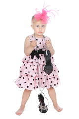 Glamour little girl trying on her mother's black shoes over whit