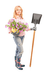 Full length portrait of a female gardener holding  flowers and a