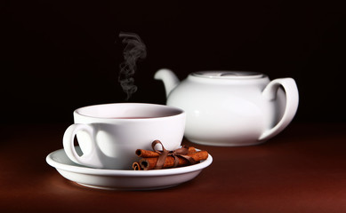 White cup and teapot on a brown background