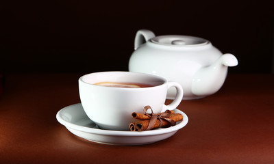 White cup and teapot on a brown background