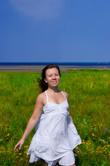Fototapeta na wymiar young happy girl walking in green field