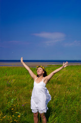 Beautiful woman stretching out her arms on a green meadow