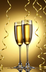 glasses of champagne and streamer on yellow background
