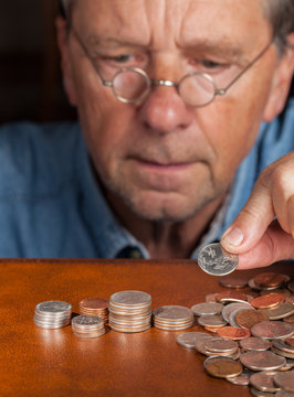 Senior Man Counting Cash Into Piles