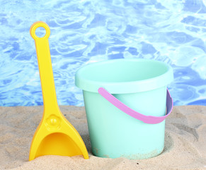 Children's beach toys on sand on water background