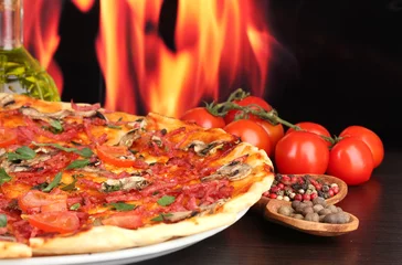 Zelfklevend Fotobehang heerlijke pizza en tomaten op houten tafel op vlam © Africa Studio