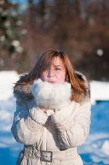 Beautiful woman blowing in the snow