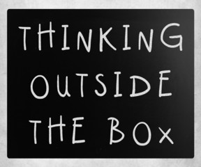 Thinking outside the box phrase, handwritten with white chalk on