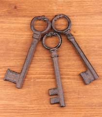 Three antique keys on wooden background