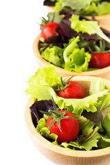 Fresh salad leaves and cherry tomatoes in wooden bowls