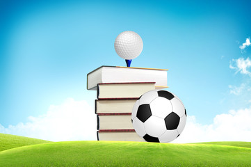 Golf ball and soccer on book tee off with green grass field over
