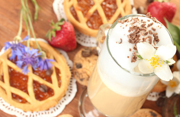glass of coffee cocktail on wooden table with sweet and flowers