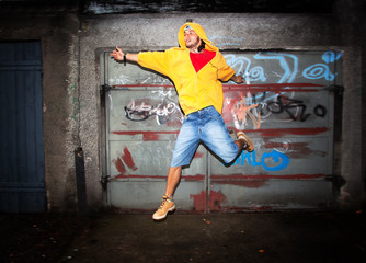 Young man jumping on grunge graffiti wall