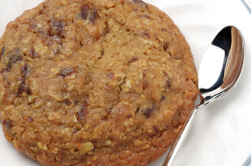 close up of oatmeal raisin cookie on white plate with spoon