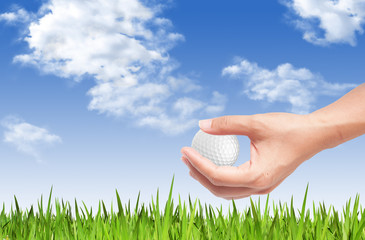 Close-up of hand holding golf ball with green grass for web desi