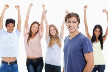 Smiling man with people behind him raising their arms