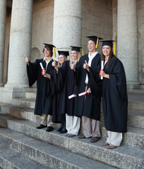 Laughing graduates posing the thumb-up
