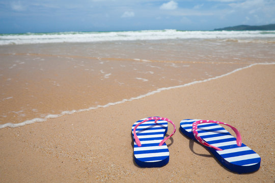 Colorful flipflop footware on sea beach. Holiday concept.
