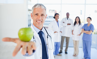 Medical team in the background looking at a doctor who is holdin
