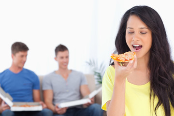 Woman about to eat a pizza slice as her friends sit behind her