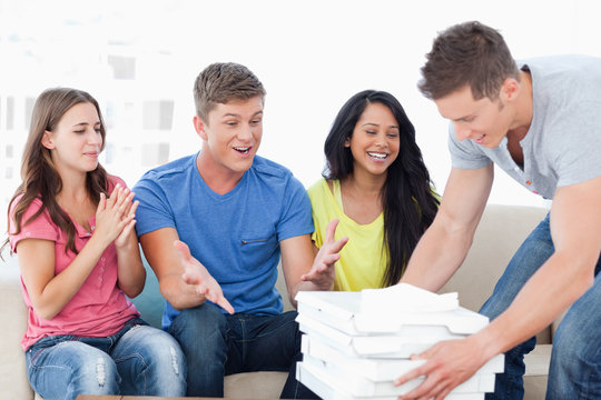 Friends celebrating as one guy brings pizza to them