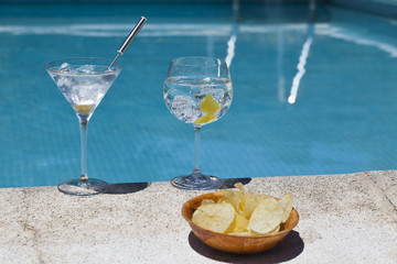 Aromatic gin tonic and mojito cocktails on swiming pool backgrou