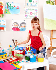 Child with picture and brush in playroom.