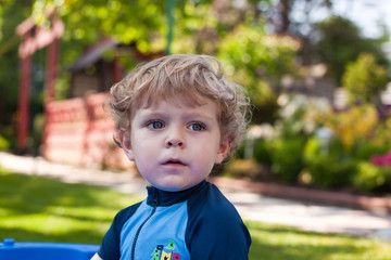 portrait of boy with blue eyes and blond curly hairs summer