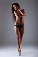 Young beautiful woman posing topless on tiptoe