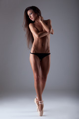 Naklejka premium Young beautiful woman posing topless on tiptoe